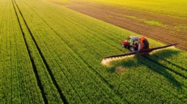 Drone,Shot,Of,A,Tractor,Spraying,In,Lush,Green,Wheat